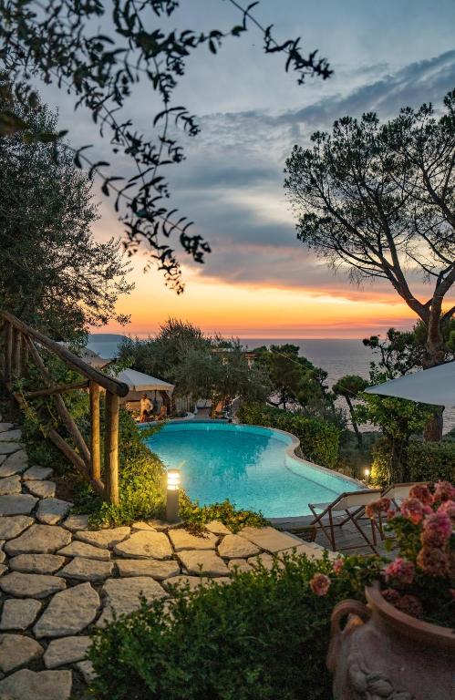 a swimming pool with a sunset in the background at Penthouse Donna Carmela in Anacapri