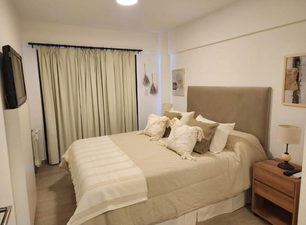 1 dormitorio con 1 cama grande con almohadas blancas en Amapola's II en Salta
