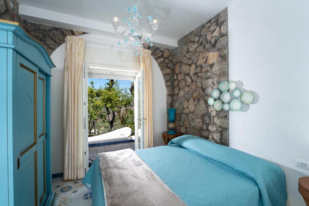 een slaapkamer met een blauw bed en een raam bij Penthouse Donna Carmela in Anacapri