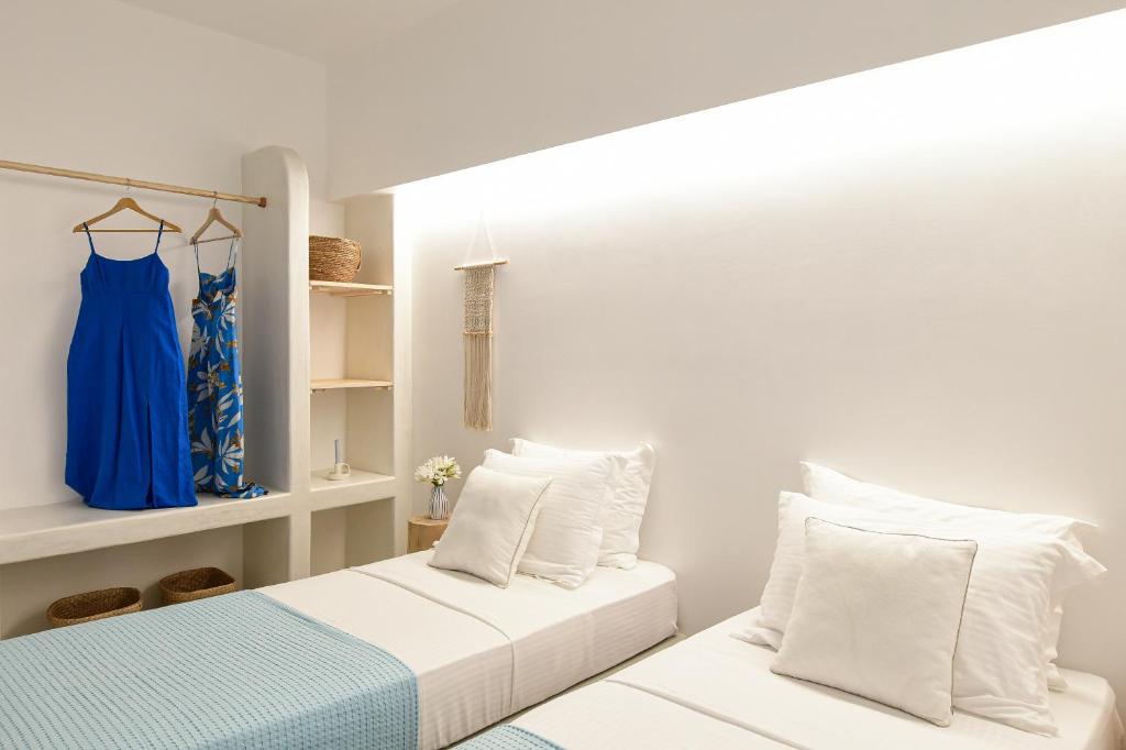 a bedroom with two beds and a blue dress on a shelf at Ios Art Suites in Ios Chora