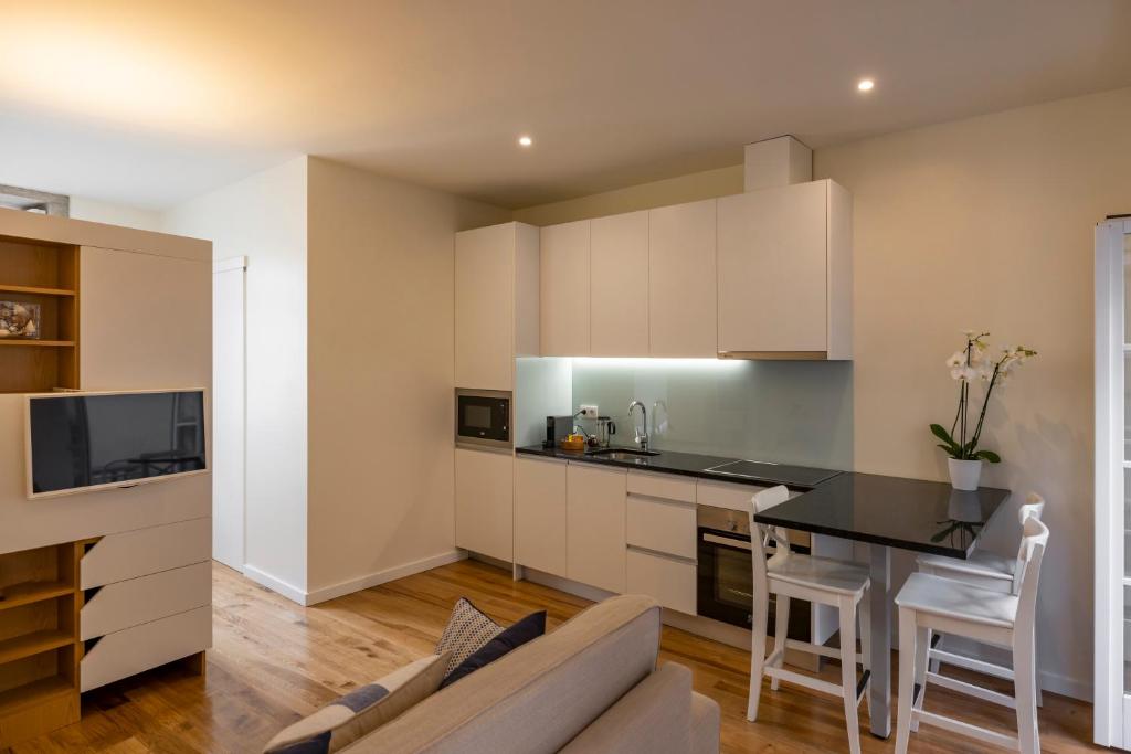 a kitchen with white cabinets and a black counter top at Bright studio with terrace in Porto