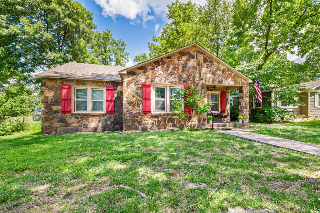 a stone house with red shutters on a lawn at The Little Rock House in Bentonville