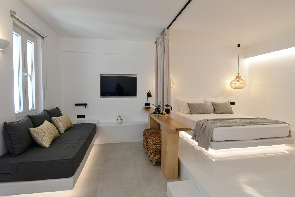 a white bedroom with a bed and a couch at Ios Art Studios & Luxury Apartments in Ios Chora