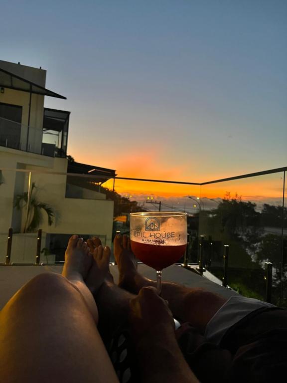 a person laying on a balcony with a glass of wine at Suítes Luxo Marambaia- Epic House in Rio de Janeiro