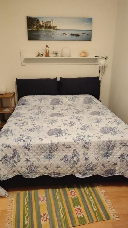 1 dormitorio con 1 cama con edredón azul y blanco en Alle rose barcolane, en Trieste