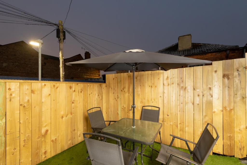 une table avec un parasol devant une clôture dans l'établissement Central Roof Terrace Apartment, à Stockton-on-Tees