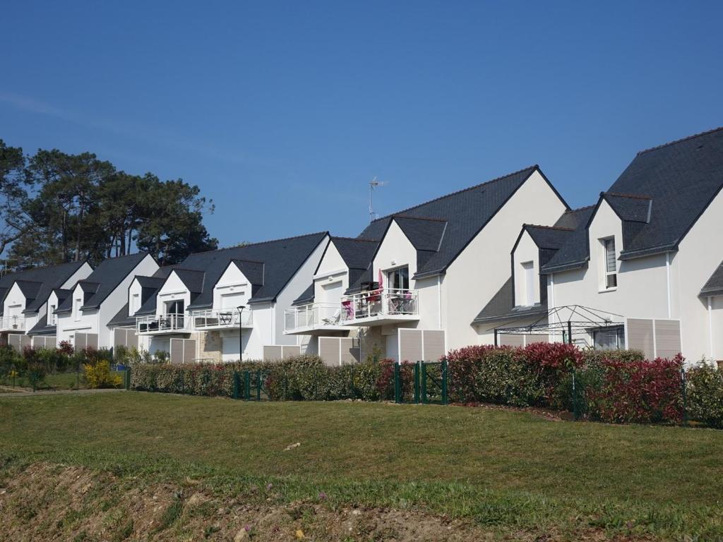 une rangée de maisons blanches aux toits noirs dans l'établissement Appartement neuf 2-4 pers, terrasse et jardin, à 400m de la plage du Rohaliguen - FR-1-639-35, à Sarzeau