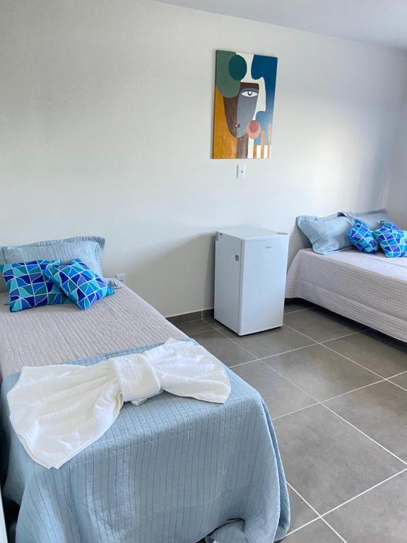 - une chambre avec deux lits et un petit réfrigérateur dans l'établissement Hanuá Beach House, à Guarapari