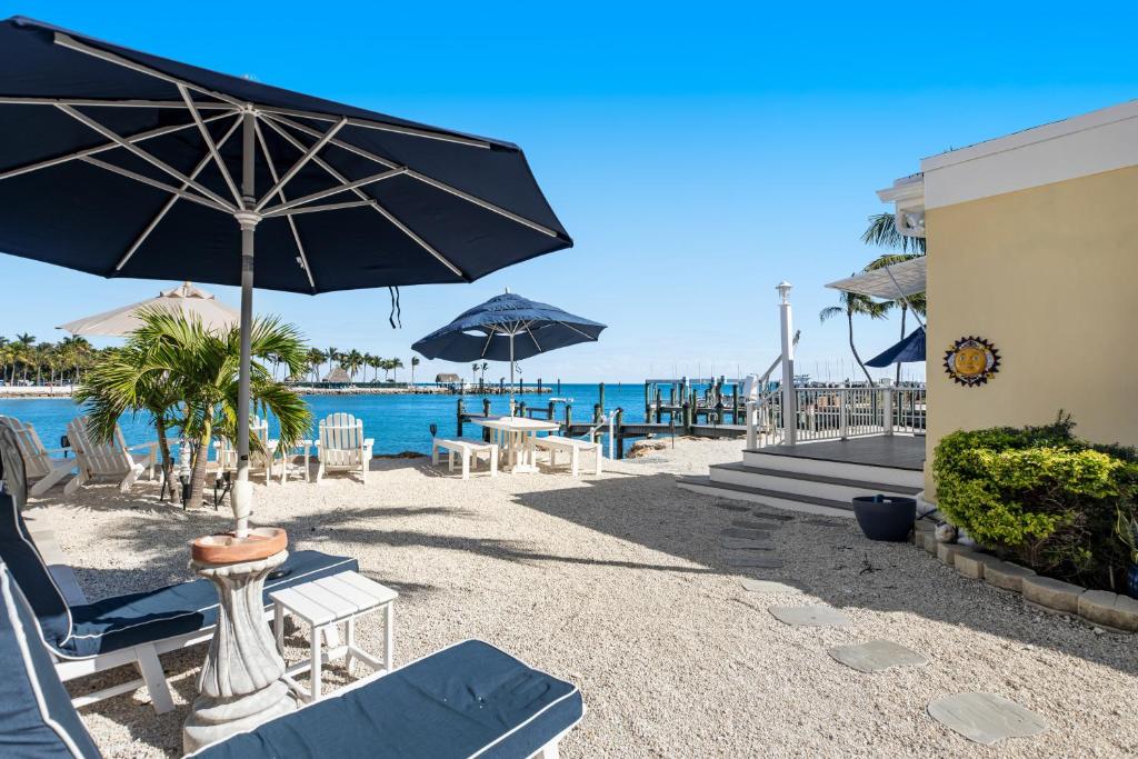 einen Strand mit Liegestühlen und Sonnenschirmen und dem Meer in der Unterkunft Casa Del Mar in Key Colony Beach