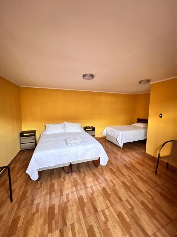 1 dormitorio con 2 camas y suelo de madera en HOSTAL APANANTOR 1 en San Pedro de Atacama