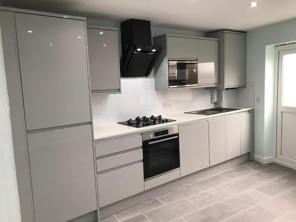 een keuken met witte kasten en een fornuis met oven bij One bedroom apartment in Goodmayes
