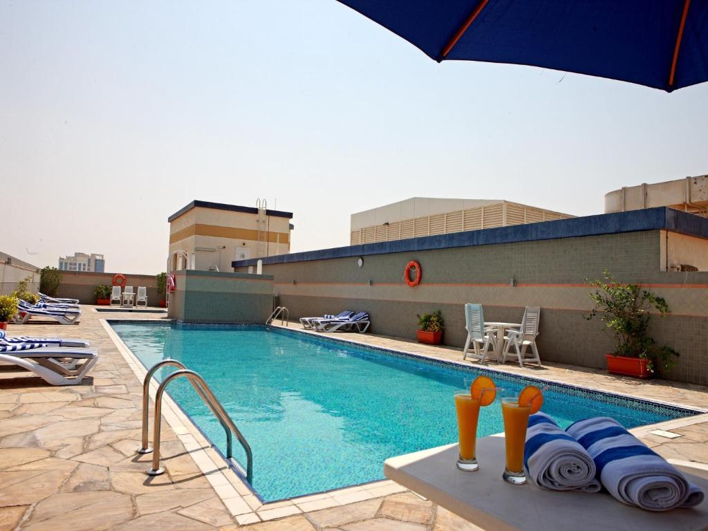 a swimming pool with a blue chair and a blue umbrella at Rose Garden Hotel Apartments - Barsha in Dubai