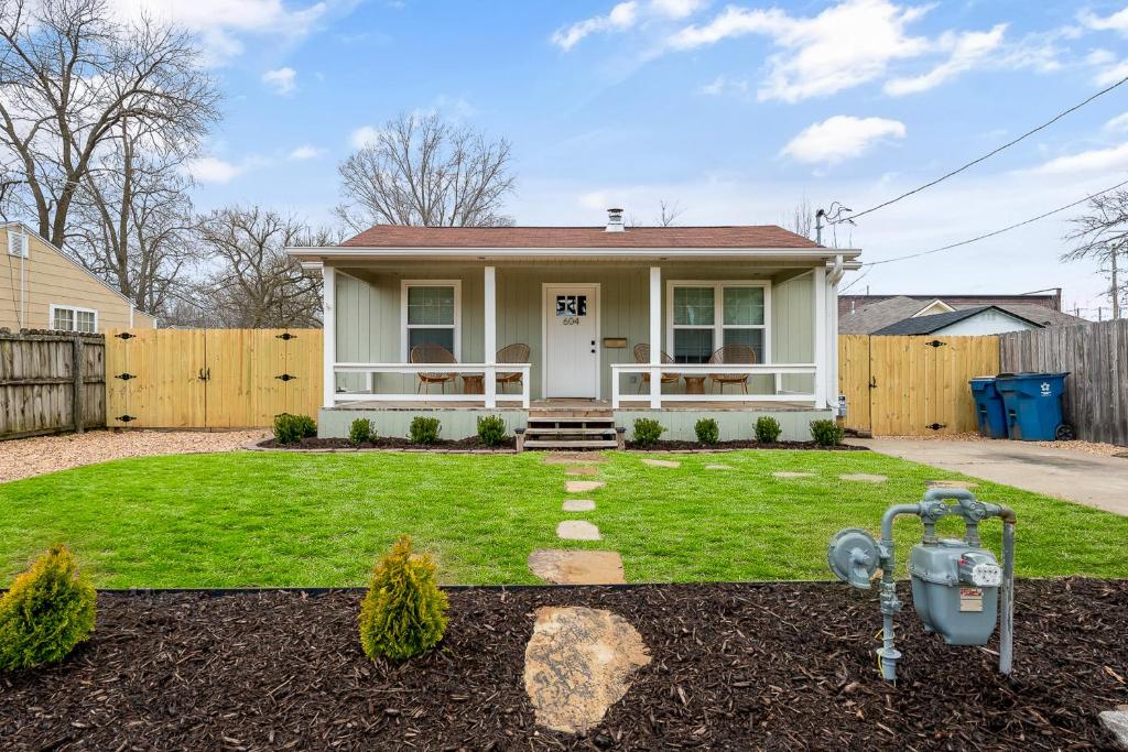 uma casa branca com uma cerca e um quintal em B Street Bungalow em Bentonville