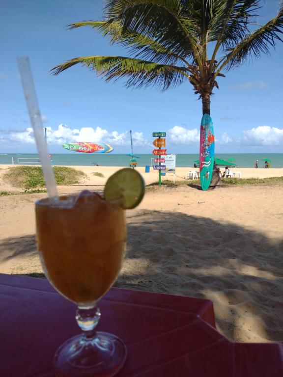 una bebida en una mesa con una playa en el fondo en Box 150 Joia Rara no Caribessa, en João Pessoa