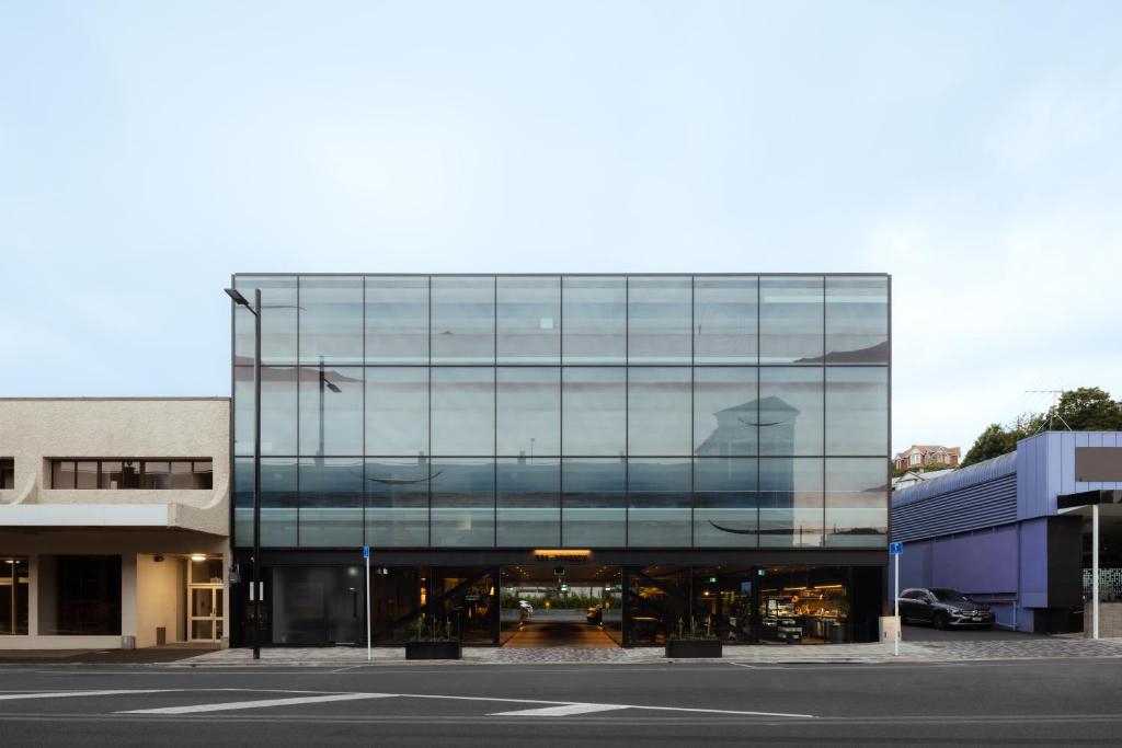 a glass building with a reflection of a person in it at Ebb-Dunedin in Dunedin