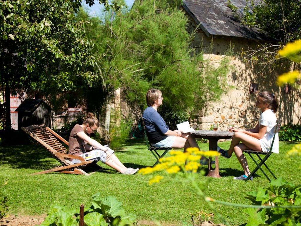 een groep mensen die rond een tafel in een tuin zitten bij Gîte Berfay, 5 pièces, 11 personnes - FR-1-410-157 in Berfay