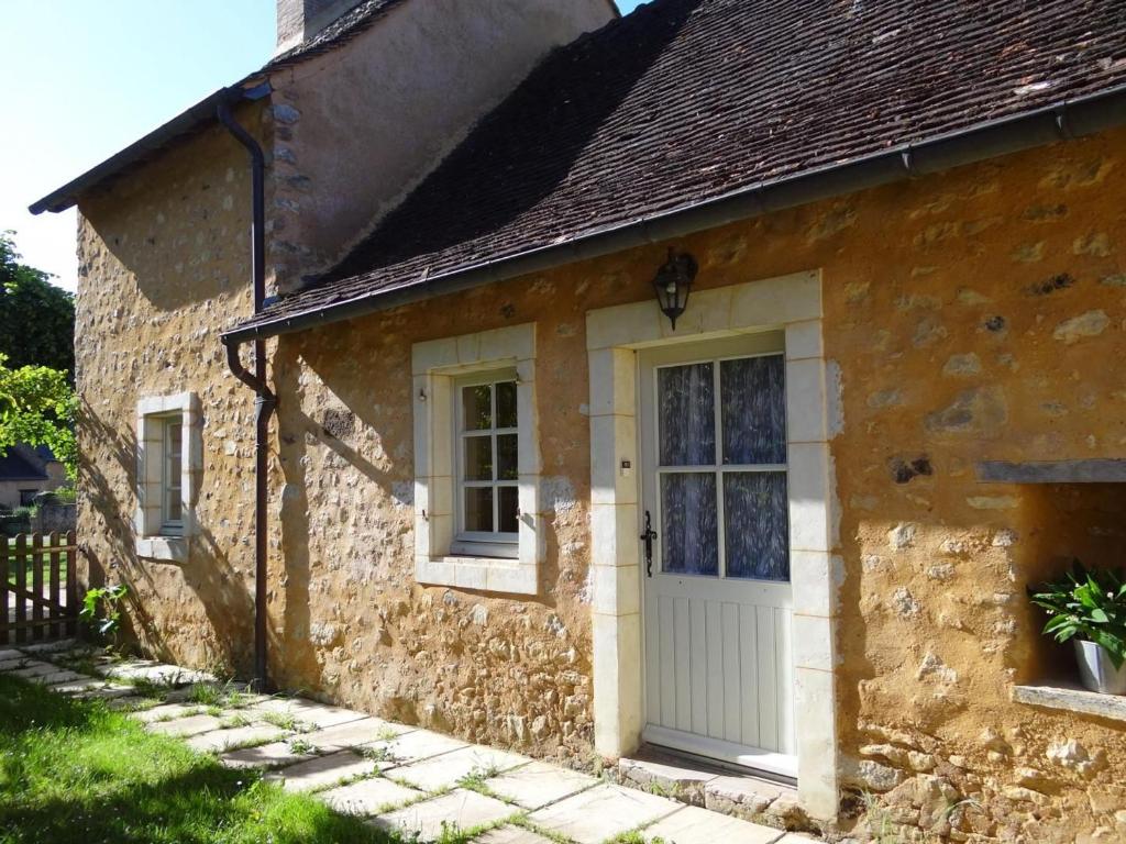 uma casa de pedra com uma porta branca e janelas em Gîte Asnières-sur-Vègre, 3 pièces, 5 personnes - FR-1-410-237 em Asnières-sur-Vègre