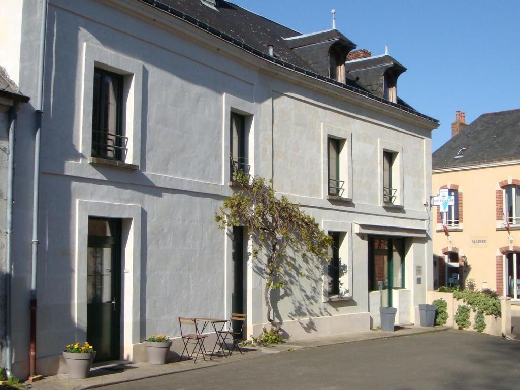 une maison blanche avec des fenêtres noires dans l'établissement Charmant Gîte Confortable avec Wifi, au Cœur d'un Village Typique près de Bercé - FR-1-410-225, à Montreuil-le-Henri