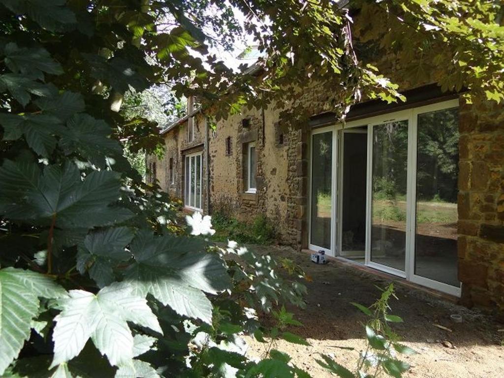 una casa de ladrillo con una gran ventana y algunas plantas en Gîte La Bazoge, 5 pièces, 7 personnes - FR-1-410-254, en La Bazoge