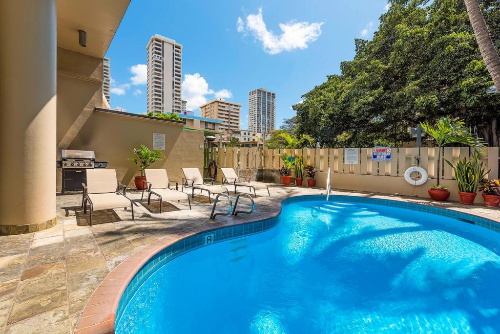 een zwembad in een achtertuin met stoelen en een hek bij @ Marbella Lane - Marina Studio near the beach in Honolulu