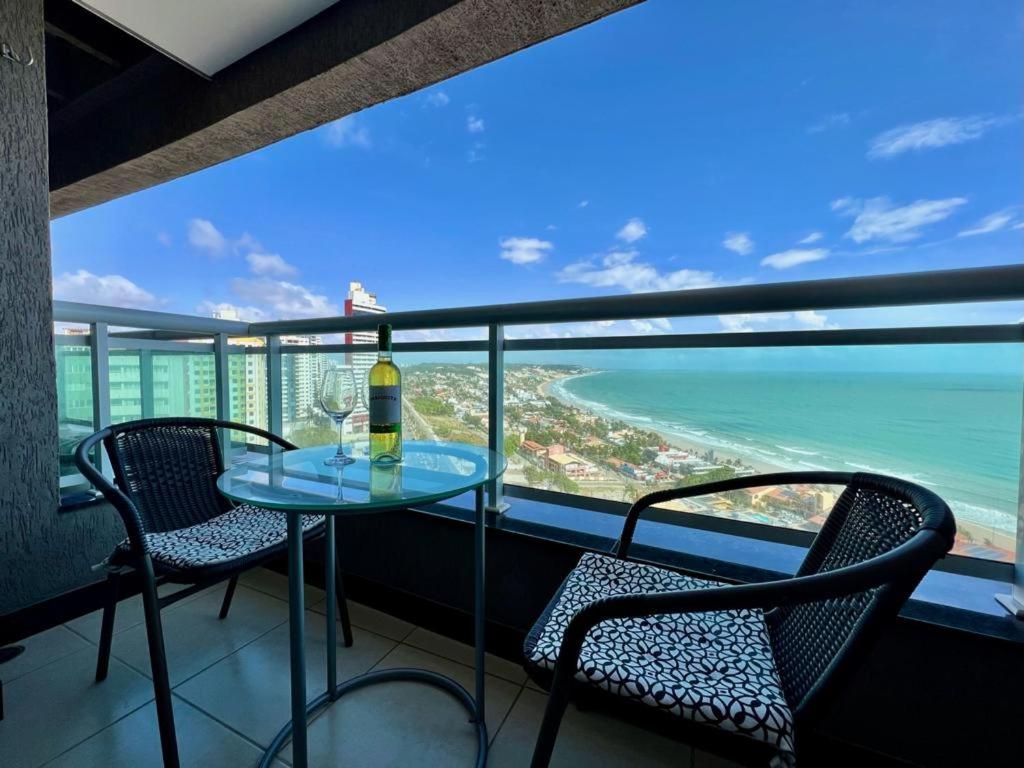 una mesa con una botella de vino en un balcón con vistas al océano en Duna Barcane Vista Mar Pontanegra Natal RN, en Natal