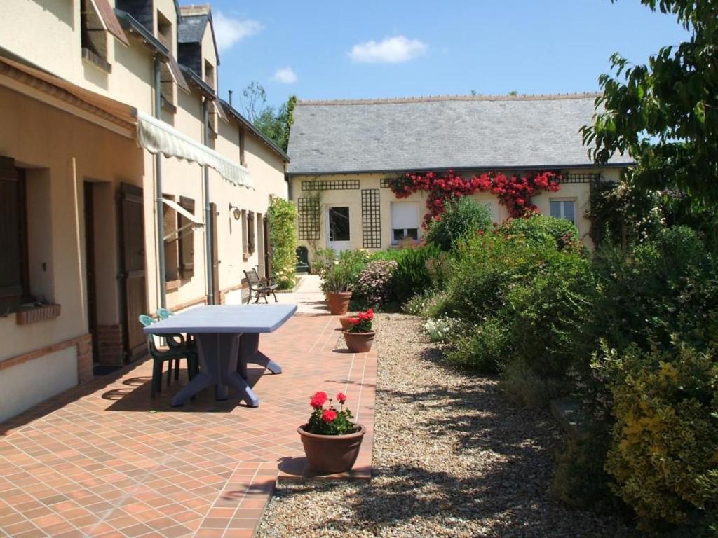 a patio with a picnic table and potted plants at Gîte spacieux avec billard, cheminée & terrasse, près de la forêt de Bercé, Wi-Fi & activités nature - FR-1-410-337 in Thoiré-sur-Dinan