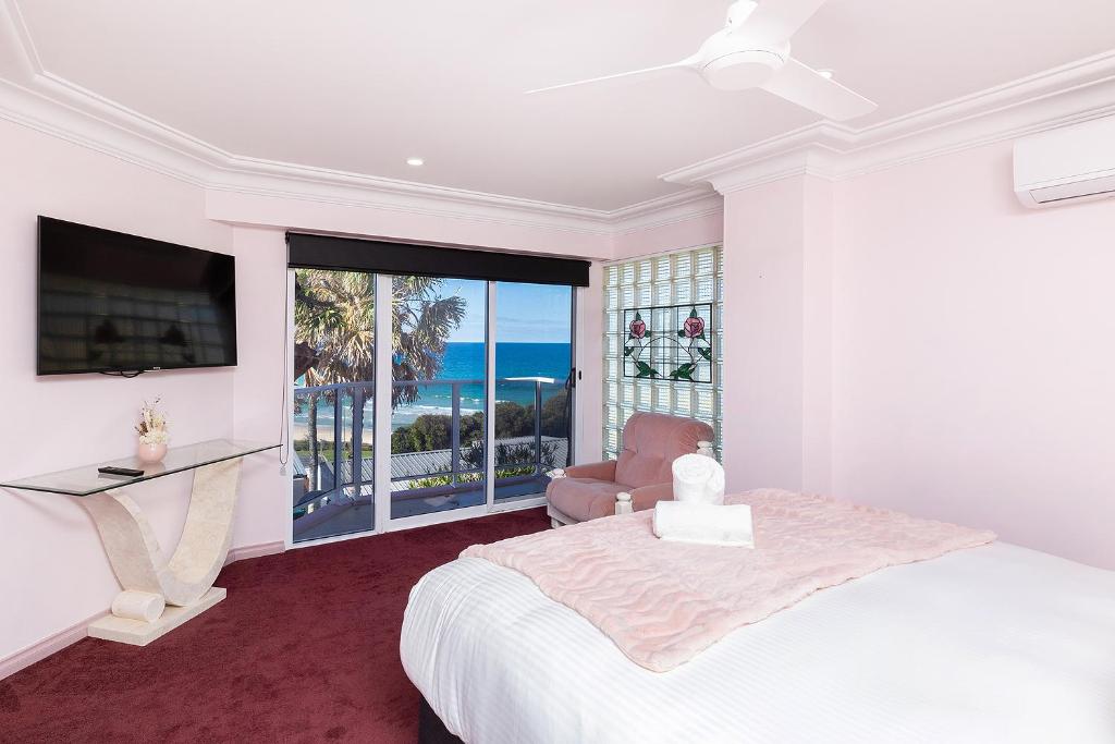 a bedroom with a bed and a desk and a window at The Pink Palace in Forster