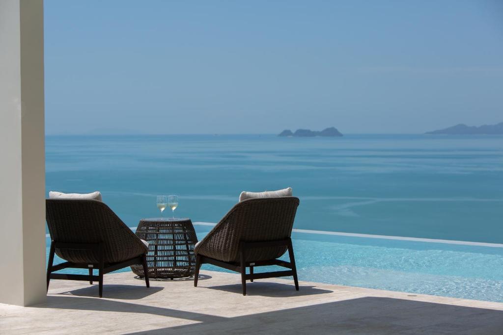 twee stoelen en een tafel met uitzicht op de oceaan bij Villa Celadon in Mae Nam