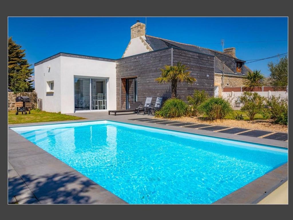 une maison avec une piscine devant une maison dans l'établissement Maison avec Piscine Chauffée, Jardin, WIFI, Proche Plages et Commodités à Erdeven - FR-1-397-53, à Erdeven