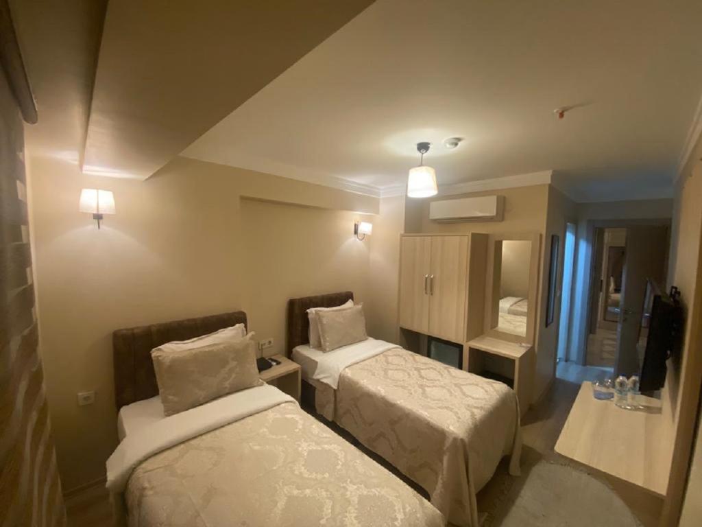 イスタンブールにあるHotel Maviremのベッド2台と鏡が備わるホテルルームです。