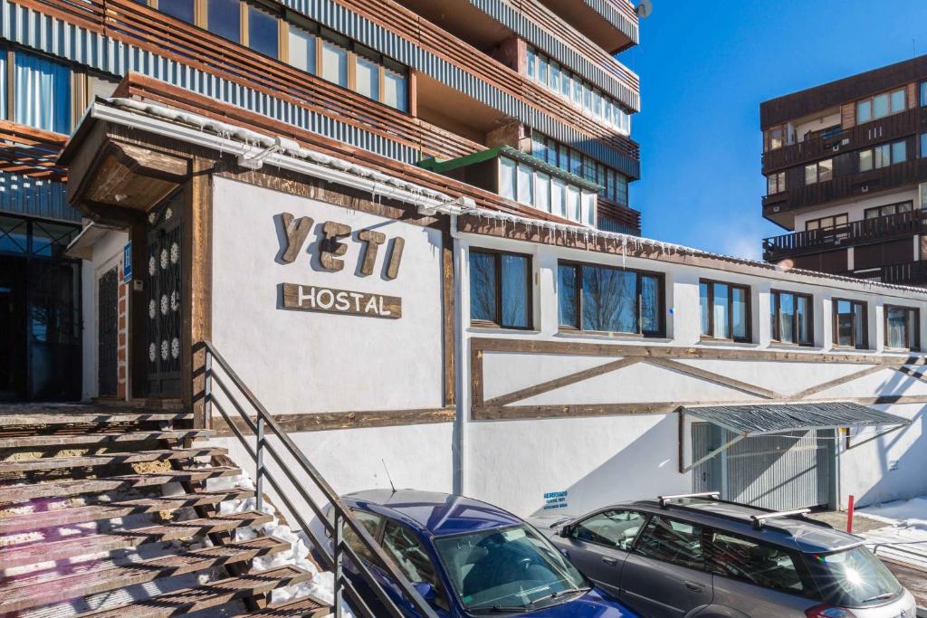 un edificio con dos coches estacionados frente a él en Hostal Yeti en Sierra Nevada