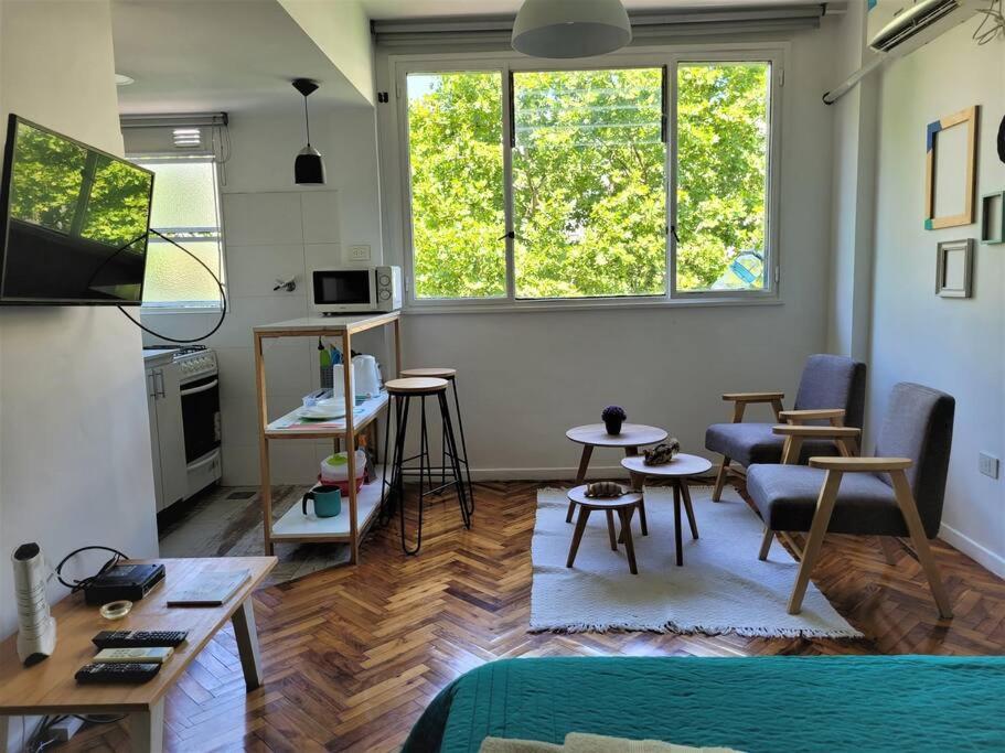 una sala de estar con mesas, sillas y una ventana en Alto Bulnes II en Buenos Aires