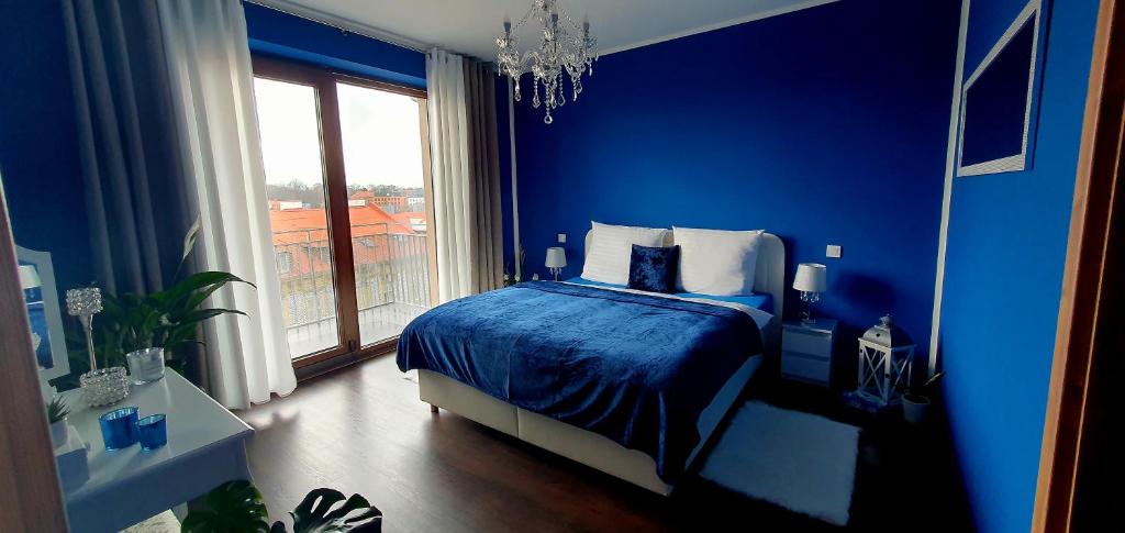 a blue bedroom with a bed and a window at Apartmán Jako doma in Olomouc