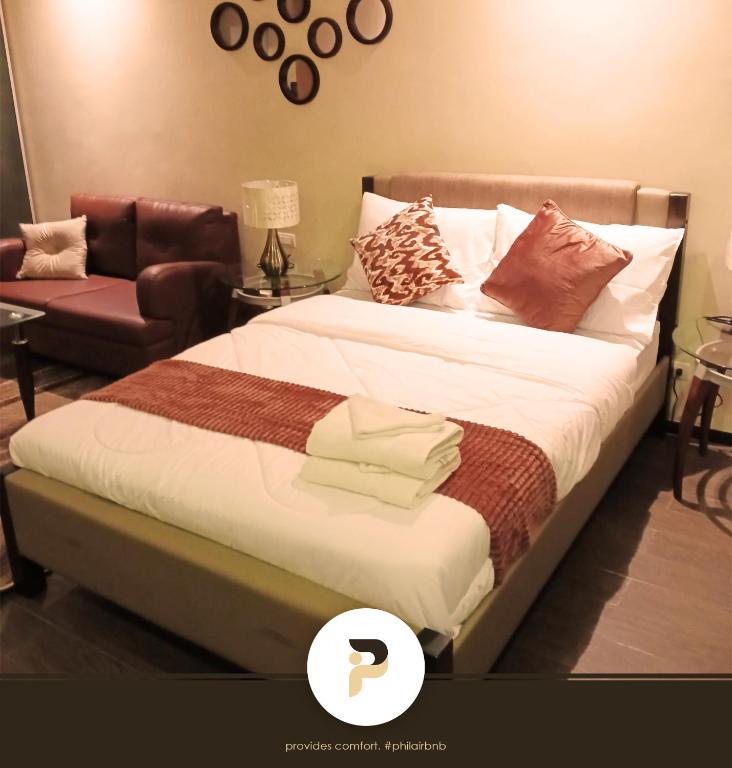 a bedroom with a bed with a chair and a couch at FULLY FURNISHED STUDIO NEAR MOA in Manila