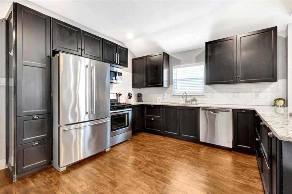 a kitchen with black cabinets and a stainless steel refrigerator at Vibrant Vacation Escape with Fast WIFI and KING BED Close to Downtown Houston! in Houston