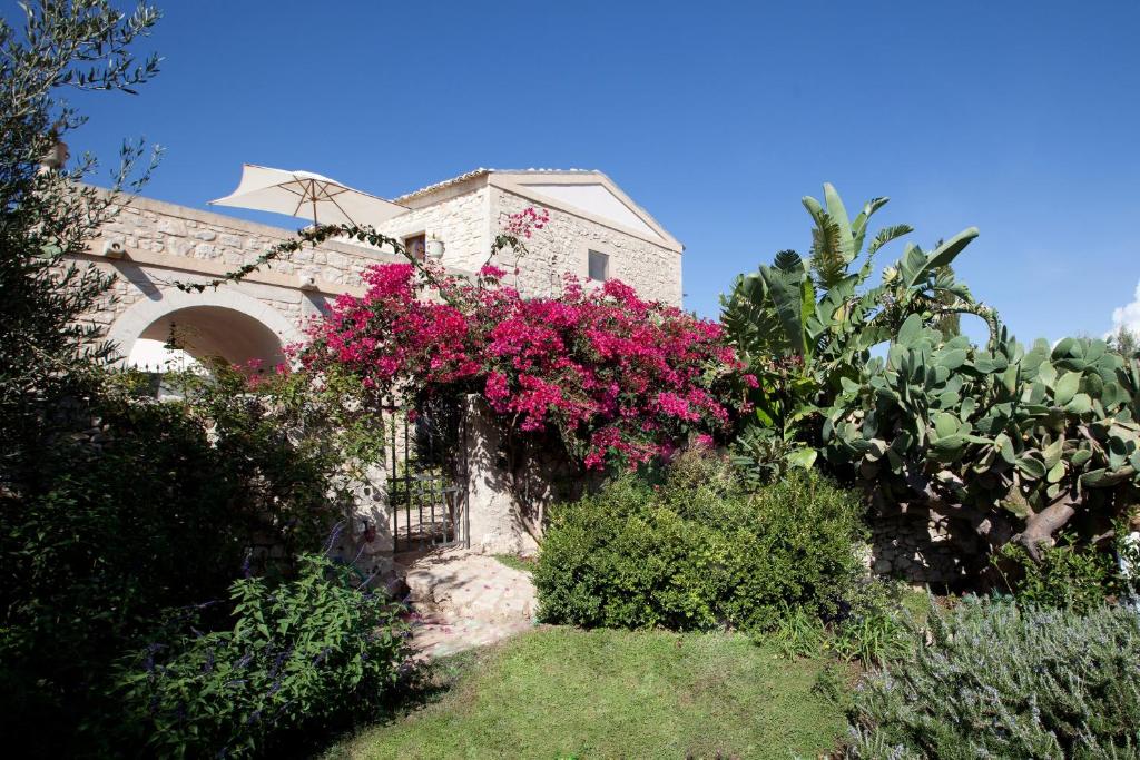 una casa con flores rosas a un lado. en Tenuta Cammarana, en Donnafugata