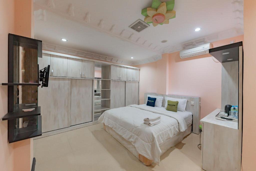 1 dormitorio con 1 cama y TV. en Urbanview Palace Syariah Balikpapan by RedDoorz, en Balikpapan
