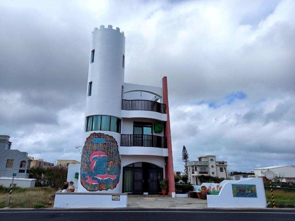 a building with a surfboard next to a lighthouse at Dreamily Fish B&amp;B in Magong