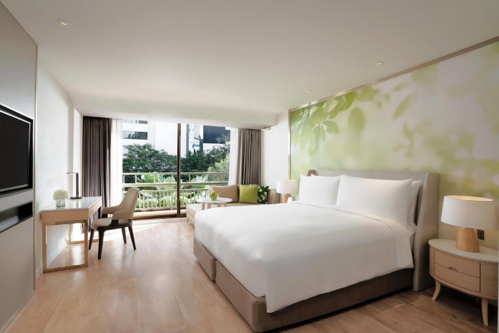 a bedroom with a large bed and a living room at Mövenpick BDMS Wellness Resort Bangkok in Bangkok