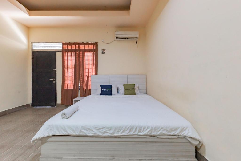 um quarto com uma grande cama branca num quarto em Urbanview Hotel Garuda Sky Inn Balikpapan by RedDoorz em Stalkudo