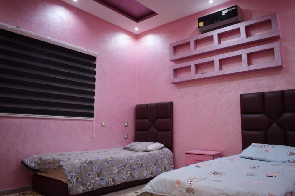 a bedroom with pink walls and two beds in it at Villa world Marrakech in Marrakesh