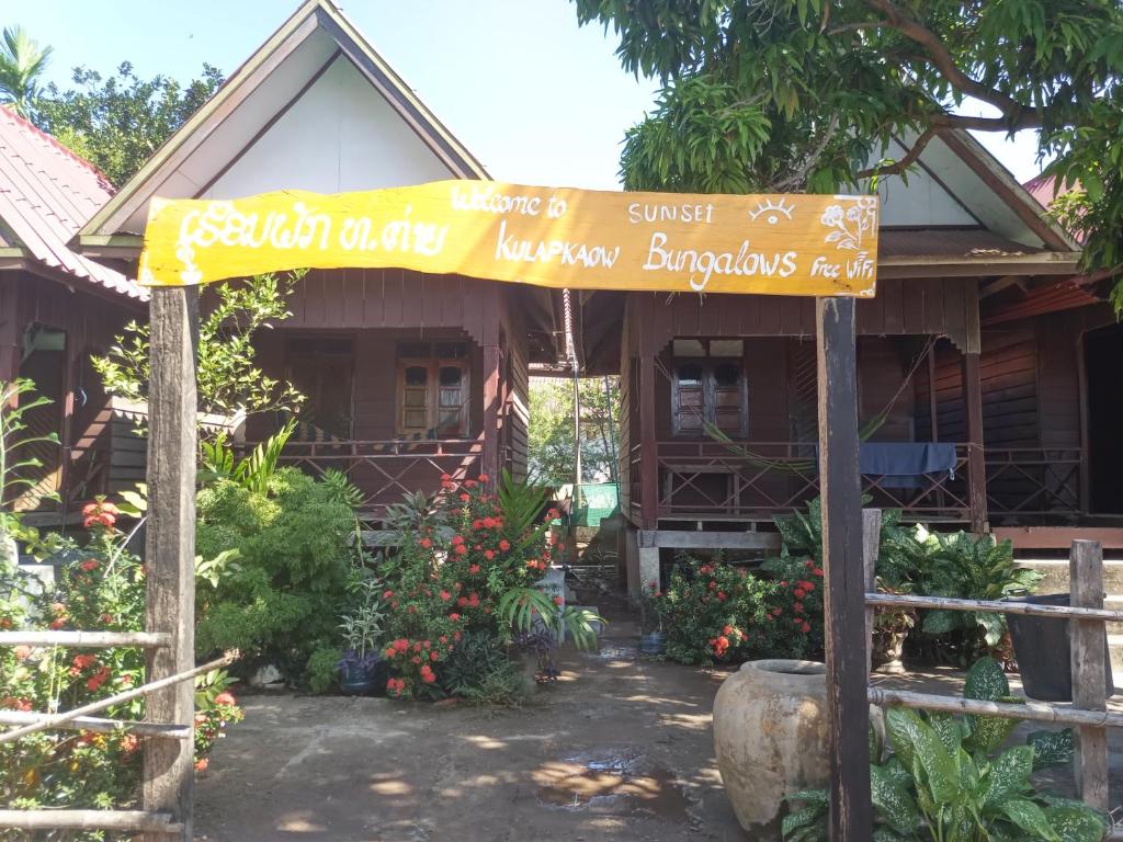 un cartel delante de una casa con flores en Kulap Kao Bungalow, en Ban Donsôm Tai