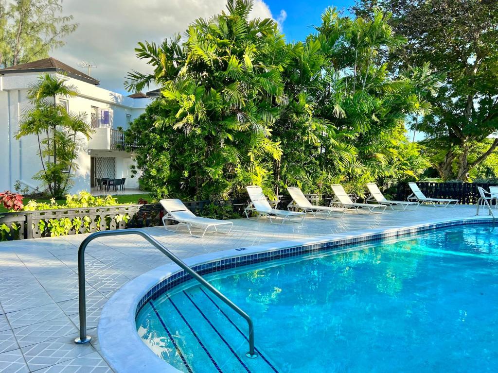 - une piscine avec des chaises longues et des arbres dans l'établissement 12 Foursquare Rockley Golf & Country Club, à Bridgetown