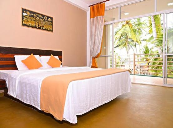 a bedroom with a large bed and a large window at Ran Dhara Beach Resort in Ambalangoda
