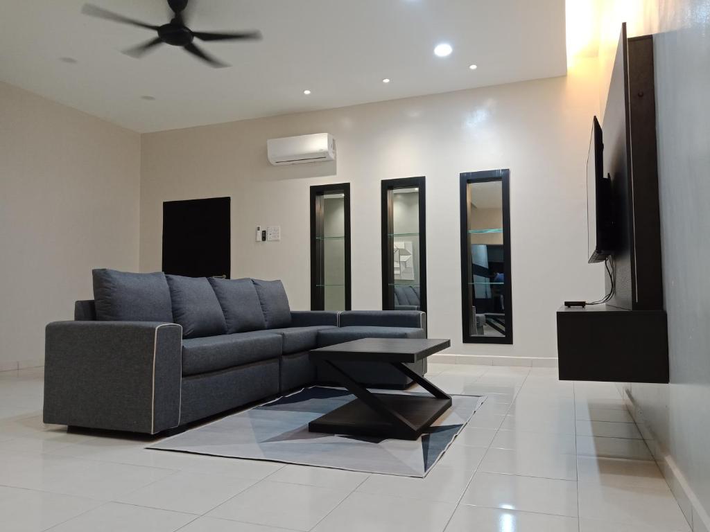 sala de estar con sofá azul y TV en 61 Homestay en Sitiawan