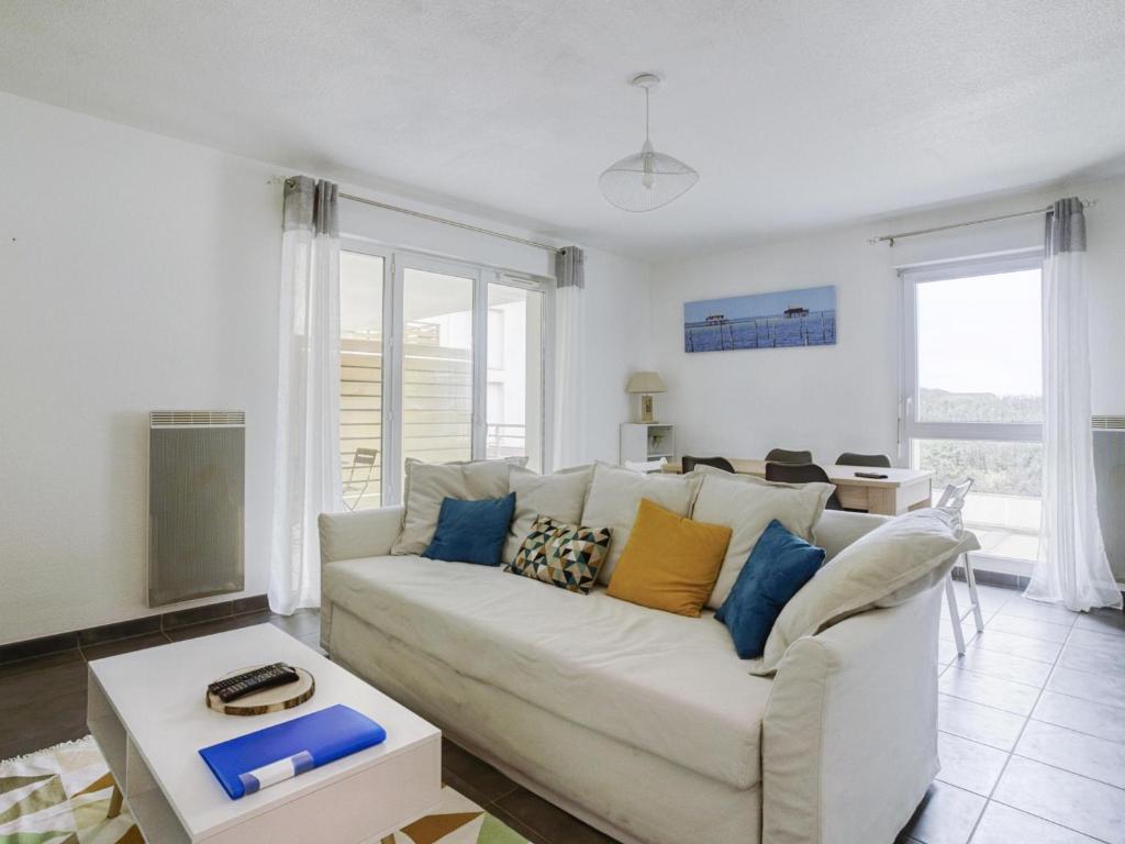 - un salon avec un canapé blanc et des oreillers colorés dans l'établissement Appartement T3 à 50m de l'océan avec terrasse, parking et Wi-Fi - Refait à neuf, centre de Biscarrosse - FR-1-521-155, à Biscarrosse
