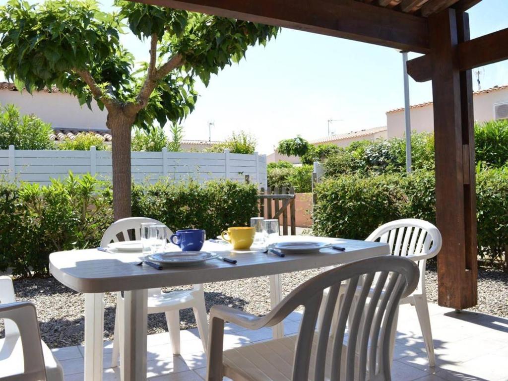 une table blanche et des chaises sur une terrasse dans l'établissement Villa Familiale 8 Pers. à 600m de la Plage avec Piscine et Terrasse Ensoleillée à Cap d'Agde - FR-1-249-103, au Cap d'Agde