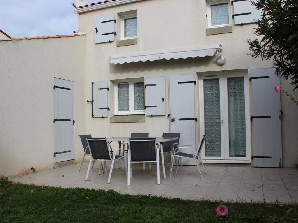 une table et des chaises devant une maison dans l'établissement Maison de Vacances à Oléron : Proche Port, Plage, Jardin, Terrasse, Garage - 6 Couchages - FR-1-246A-62, à Saint-Pierre-dʼOléron