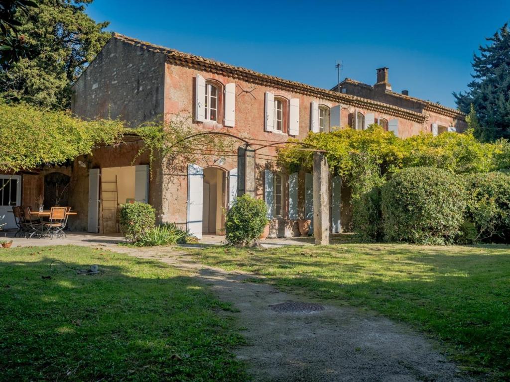 ein großes Backsteinhaus mit einem Rasenhof in der Unterkunft Maison Saint-Rémy-de-Provence, 8 pièces, 12 personnes - FR-1-599-4 in Saint-Rémy-de-Provence