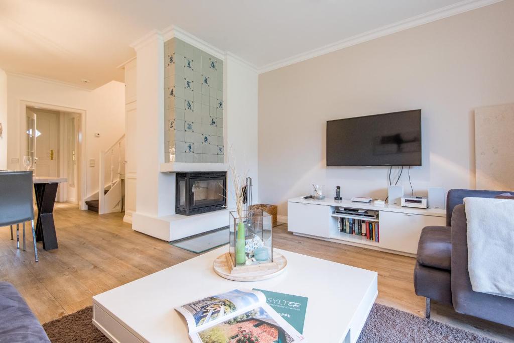 a living room with a fireplace and a tv at Haus Ameland, App 3 in Wenningstedt